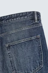 Jeans de denim de algodón, color azul oscuro con efecto lavado. Presentan un corte muy holgado (baggy fit) en toda la pierna y tiro medio. Tienen cinco bolsillos y cierre frontal con cremallera y botón.