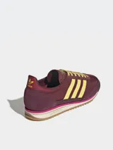 Zapatillas Adidas SL 72 OG W, color borgoña con rayas amarillas y detalles en fucsia. Inspiradas en el modelo original de 1972, con exterior de piel y revestimientos de gamuza.