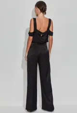 Pantalón negro de satén con corte recto y cintura alta. Presenta una abertura lateral con botones revestidos y cierre trasero invisible.