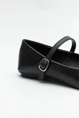 Balerina de cuero sintético negro con textura grabada, cuenta con una tira ajustable sobre el empeine con hebilla metálica.