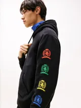 Buzo negro con capucha y cordón ajustable. Tiene un bolsillo tipo canguro y puños y bajo de punto canalé. Presenta un logo oversize del escudo de Tommy Jeans en la parte trasera, un escudo de Tommy Jeans en las mangas y un logo de Tommy Jeans bordado en el pecho.