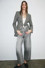 Blazer Zara de corte asimétrico confeccionado en tejido con lana. Presenta un diseño de cuadros, cuello con solapas de muesca, manga larga y cierre frontal cruzado con botones. El bajo es asimétrico con una abertura pronunciada en la espalda y cuenta con forro interior.