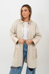 Camisa larga color beige de tejido de punto en algodón, con cuello camisero, cierre frontal con botones a presión y detalles en cuero color dorado en cuello, solapa, puños y bolsillos frontales.