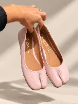 Zapatos planos estilo Tabi de cuero color rosado, con diseño de punta dividida.