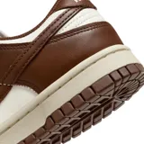 Championes Nike Dunk Low con diseño bicolor en tonos marrón y blanco. Presentan una silueta clásica de perfil bajo con paneles de cuero, puntera perforada para mayor ventilación y suela de goma resistente.