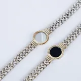 Pulsera de eslabones trenzados en plata con detalle central circular en oro que enmarca una piedra de ónix negra.