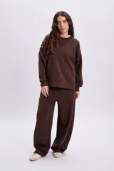 Pantalón deportivo marrón de corte barrel, estilo ancho y holgado, con cintura elástica.
