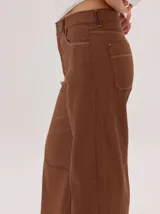 Pantalon de corte ancho y holgado, color verde militar, con diseño de tiro medio, pinzas decorativas debajo de la rodilla, bordado de monograma en el bolsillo delantero y costuras a contratono.