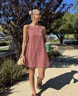 Vestido corto sin mangas de color celeste, con diseño cruzado en el frente y detalles de botones grandes en el lateral del escote.