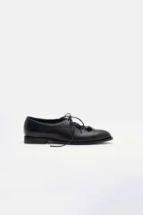 Zapato de cuero negro con cordones, diseño clásico de estilo oxford con punta redondeada y suela plana.