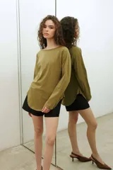 Remera de manga larga estilo raglan, color verde militar, con cuello redondo y dobladillo inferior curvado.