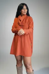 Polerón oversize de tejido de punto color naranja, con cuello alto tipo polera, mangas largas con puños acanalados y bolsillos laterales. Presenta un detalle de etiqueta de cuero en la parte inferior.