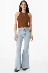 Pantalón de jean azul oscuro, corte acampanado (flare) de tiro alto, con costuras visibles en contraste y bordados tonales en la parte inferior de las piernas. El ruedo es deshilachado.