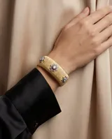 Brazalete ancho de bronce con acabado texturizado dorado, adornado con tres apliques en forma de estrella con circonias incrustadas.