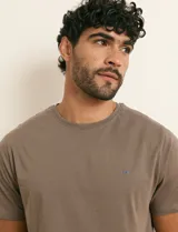 Remera básica de algodón color beige, de manga corta, con cuello redondo y un pequeño detalle bordado en el pecho.