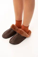 Pantuflas de cuero color chocolate con interior de piel sintética al tono y suela plana.