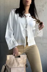 Chaqueta blanca de algodón con bordados florales en puños y ruedo, escote con lazos y mangas largas acampanadas.