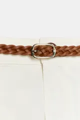 Pantalón chino color beige de tiro medio con bolsillos frontales y falsos bolsillos de vivo en la espalda. El bajo tiene un acabado con vuelta. Incluye un cinturón trenzado marrón.