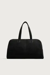 Bolso de viaje de diseño minimalista confeccionado en piel con acabado serraje. Cuenta con compartimento principal con cierre de cremallera e imanes, interior con bolsillos organizadores y doble asa de mano en piel.