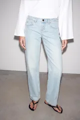 Jeans de mezclilla en color negro gastado, tiro bajo, corte de pernera recta y diseño clásico de cinco bolsillos con cierre frontal de cremallera y botón metálico.