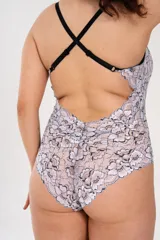 Body blanco con estampado de flores negras, confeccionado en puntilla elastizada. Breteles elásticos regulables cruzados en la espalda. Broche en la entrepierna con fundillo en algodón 100%.