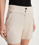 Bermuda roja de poliéster con cintura elástica, bolsillos laterales y cierre con cremallera y botones.