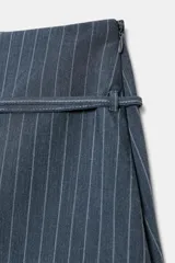 Falda pantalón (skort) de tiro medio, color azul grisáceo con finas rayas verticales blancas. Presenta un cinturón fino con hebilla metálica rectangular y cierre lateral oculto.