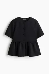 Top negro de manga corta con escote redondo y cierre frontal de botones forrados. Presenta un corte peplum con volado en la cintura.