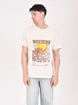 Remera de algodón color blanco con estampa frontal temática western que incluye un sol amarillo y un paisaje desértico con tipografía en tonos marrones.