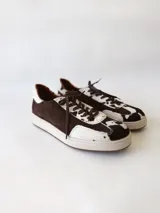 Zapatilla deportiva de cuero con estampado de vaca (pelo), color marrón y blanco. Suela blanca gruesa.