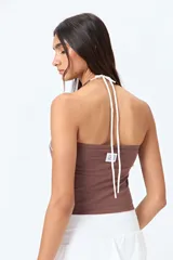 Top halter negro con escote en V y detalle de vivo blanco horizontal. Presenta un diseño ajustado al cuerpo y espalda descubierta con tiras regulables.