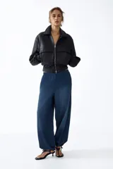 Pantalón tobillero en denim suave de corte holgado con piernas globo, cintura elástica y bolsillos laterales discretos, con abertura ajustable mediante cordón en los bajos.