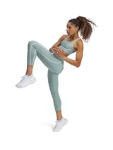 Top deportivo Under Armour de soporte medio, color verde menta con detalles de ribete blanco en el escote y bajo el busto. Presenta diseño de espalda abierta, almohadillas moldeadas y tejido de secado rápido.