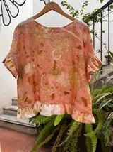 Top de lino con estampado botánico artesanal (ecoprint) en tonos rosados y ocres. Presenta mangas cortas con volados y un volado decorativo en el ruedo inferior en color blanco.