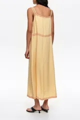 Vestido midi de línea A color amarillo, confeccionado en mezcla de lyocell y viscosa, con botones frontales, escote cuadrado y tirantes finos. Presenta detalles de encaje en contraste y mini tablas verticales en el frente.