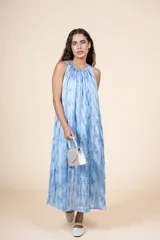 Vestido midi de corte amplio y silueta recta, con cuello redondo y diseño sin mangas. Presenta un estampado tipo tie-dye en tonos azules y blancos, confeccionado en una mezcla de algodón y poliéster.
