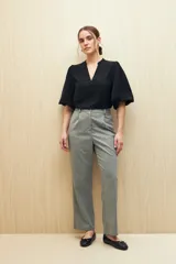 Blusa de color marrón con escote en V y mangas 3/4 con diseño acampanado. Presenta un sutil frunce en los hombros y una silueta relajada.