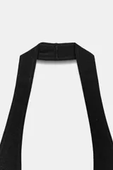 Vestido midi negro, confeccionado en tejido de punto, con escote halter y espalda descubierta. La falda es acampanada y con caída.