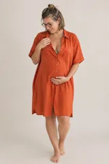 Camisa maternal color naranja, de corte holgado, con mangas cortas, cuello camisero y cierre frontal de botones. Cuenta con un pequeño bordado de corazón en el pecho.