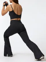 Calza flare deportiva de tiro alto color negro, confeccionada en poliéster con spandex. Presenta pretina ancha, bolsillos laterales y una pequeña apertura en el dobladillo inferior de cada pierna.