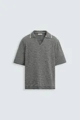 Polo de punto de manga corta con cuello solapa y abertura frontal en forma de V. Presenta un patrón de rayas horizontales finas en blanco y negro, con un acabado texturizado y un calce relajado.