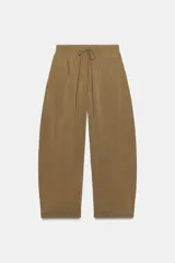 Pantalón fluido confeccionado en mezcla de modal, de tiro medio con cintura elástica ajustable con cordón y bolsillos laterales, en color tostado.
