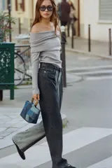Jersey de punto liso color negro, con escote recto tipo off-shoulder con vuelta y manga larga.