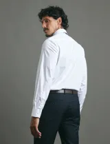 Camisa de vestir de manga larga, confeccionada en popelina fina de algodón, con cuello clásico y cierre frontal de botones.