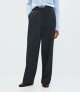 Pantalón de corte recto confeccionado en punto roma con estampado de cuadros. Presenta cintura estructurada con pliegues delanteros, trabillas para cinturón y cierre frontal. Incluye un cinturón fino con hebilla metálica.