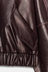 Chaqueta bomber de estilo oversize confeccionada en material efecto piel con acabado brillante. Presenta cuello redondo, cierre frontal con cremallera metálica, bolsillos laterales de vivo y bajo con elástico.