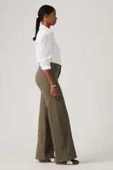 Pantalón de jean estilo wide leg en color verde oliva, con costuras verticales frontales que recorren el largo de las piernas. Presenta un diseño de tiro medio con cierre de botón y cremallera, y bolsillos laterales.