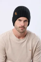 Gorro tejido de punto grueso con diseño acanalado y vuelta en el borde. Incluye una pequeña etiqueta de cuero sintético en el lateral.