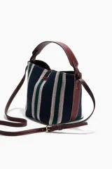 Cartera bombonera con estampado a rayas en tonos azul marino, verde y blanco, con detalles de asa y correa ajustable en material sintético marrón oscuro. Cuenta con cierre de trabilla con herraje metálico en la parte superior.