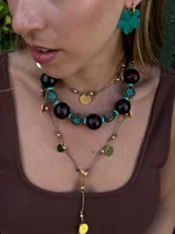 Collar corto con cuentas de madera color marrón oscuro, cuentas tibetanas con incrustaciones de color turquesa y detalles en metal color bronce. Cierre con cadena de acero quirúrgico y gancho para regular el largo.